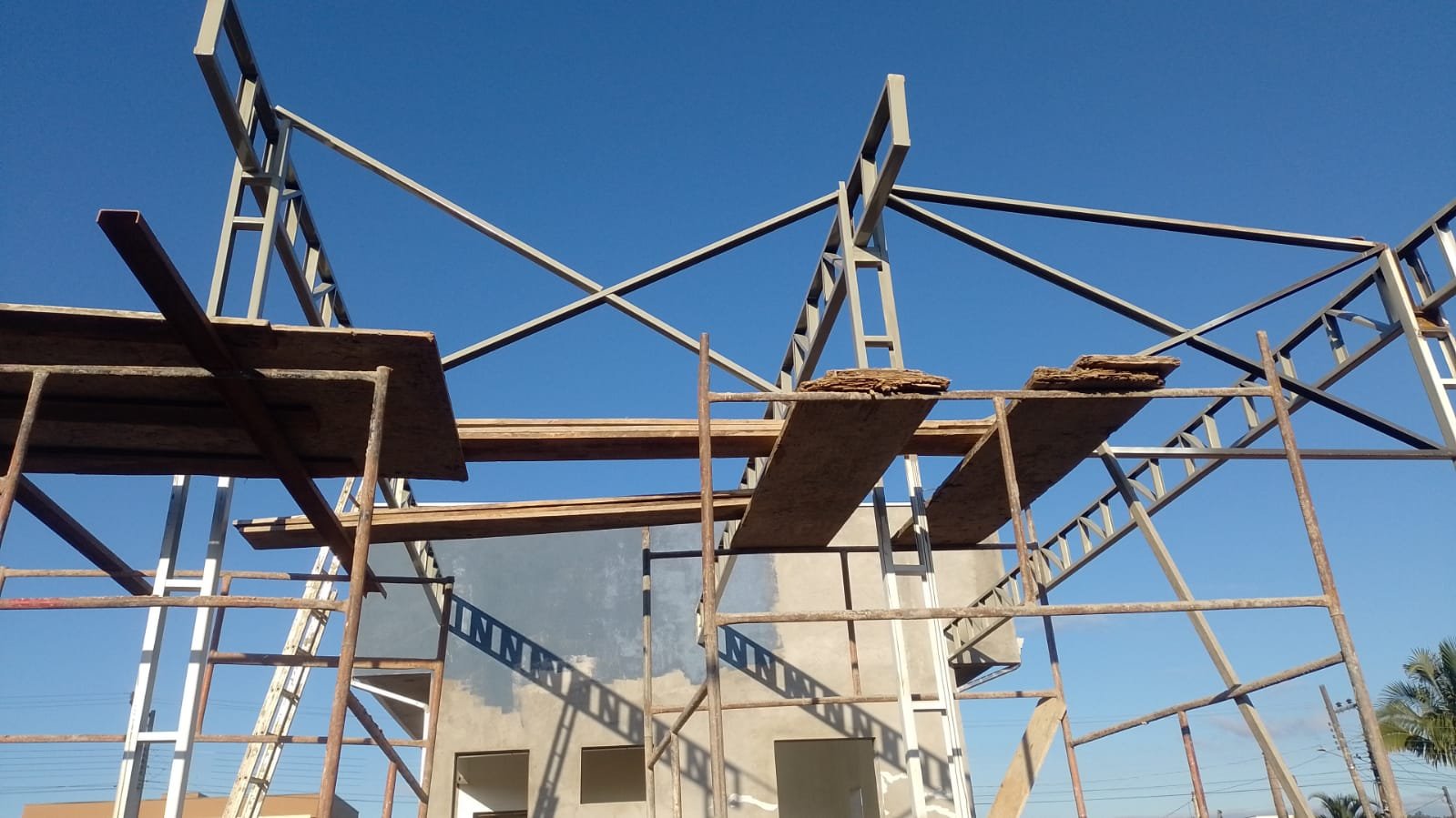 Treliças metálicas sendo montadas sobre a edificação